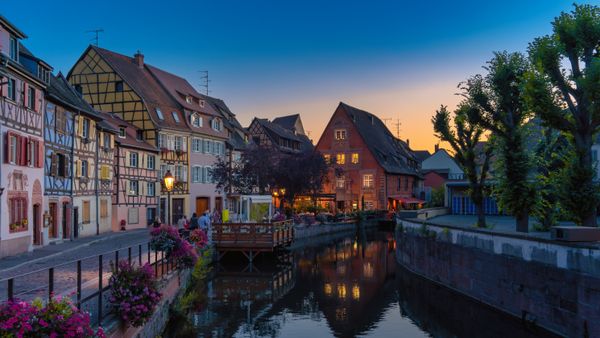 Picturesque European canal lined with half-timbered houses at sunset, Colmar-style autumn city scene